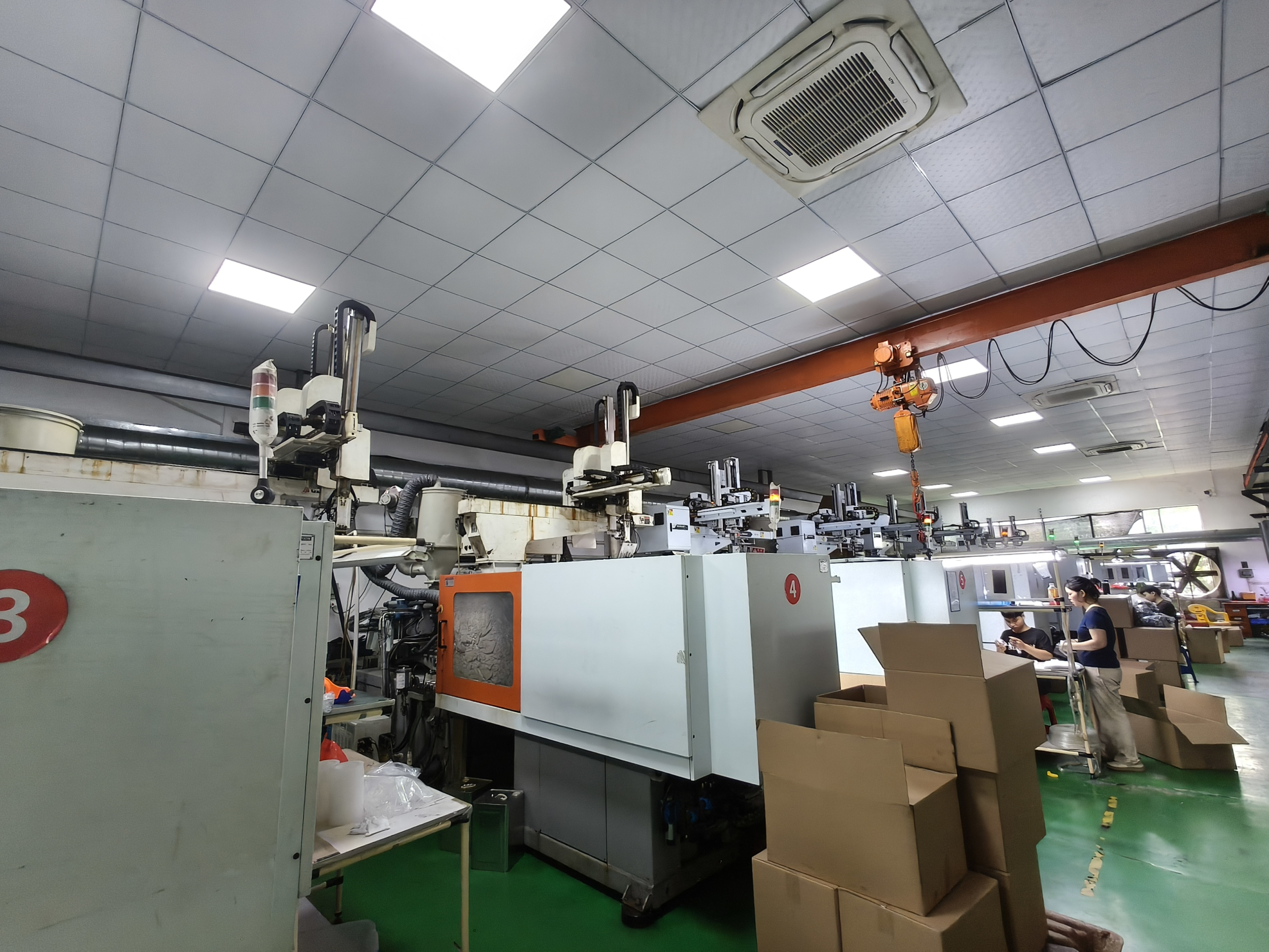 Workers operating injection molding machines in production workshop